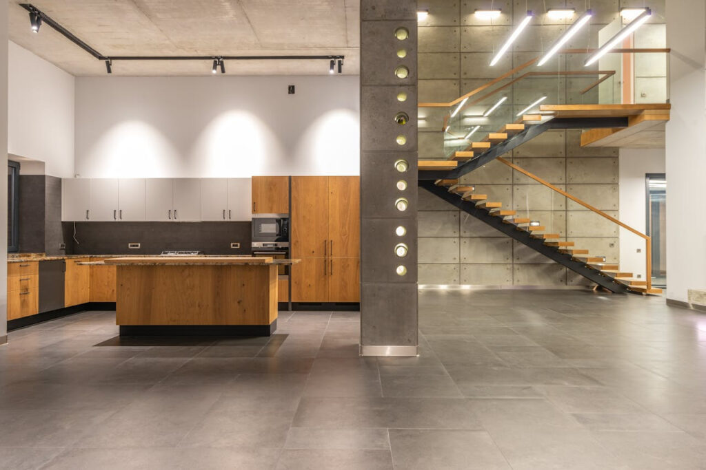 Contemporary kitchen with wooden cabinetry and sleek floating staircase in open design.